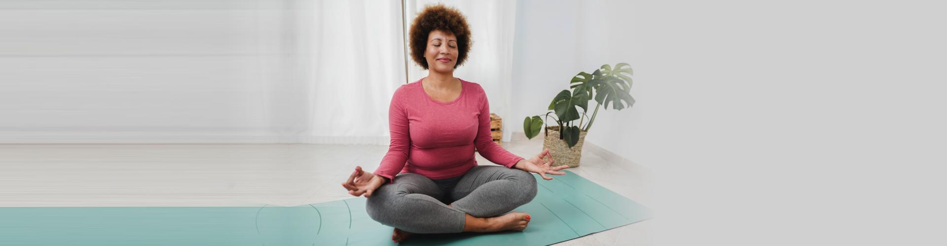 African senior woman doing yoga session at home